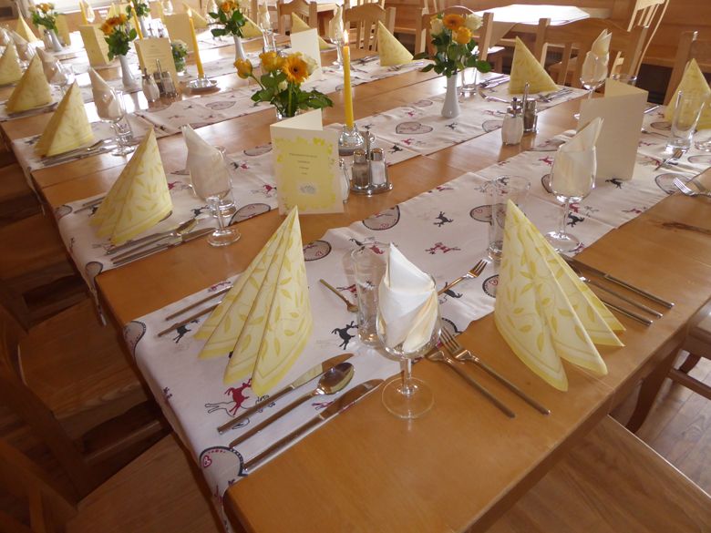 Festively laid table in an Alpine inn with yellow napkins and flowers.