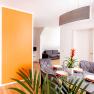 Modern apartment with dining area, orange wall and gray sofa.