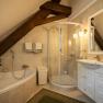 An elegant bathroom with bathtub, shower and washbasin under a sloping roof.