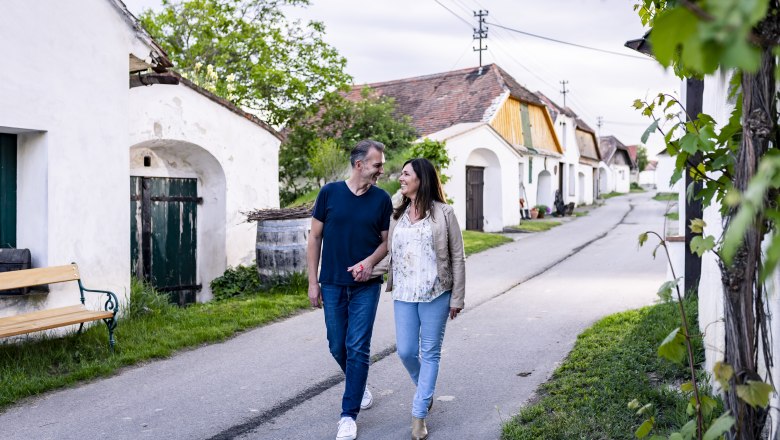 A couple walks through the wine cellar lane in Zellerndorf, surrounded by traditional wine cellars.