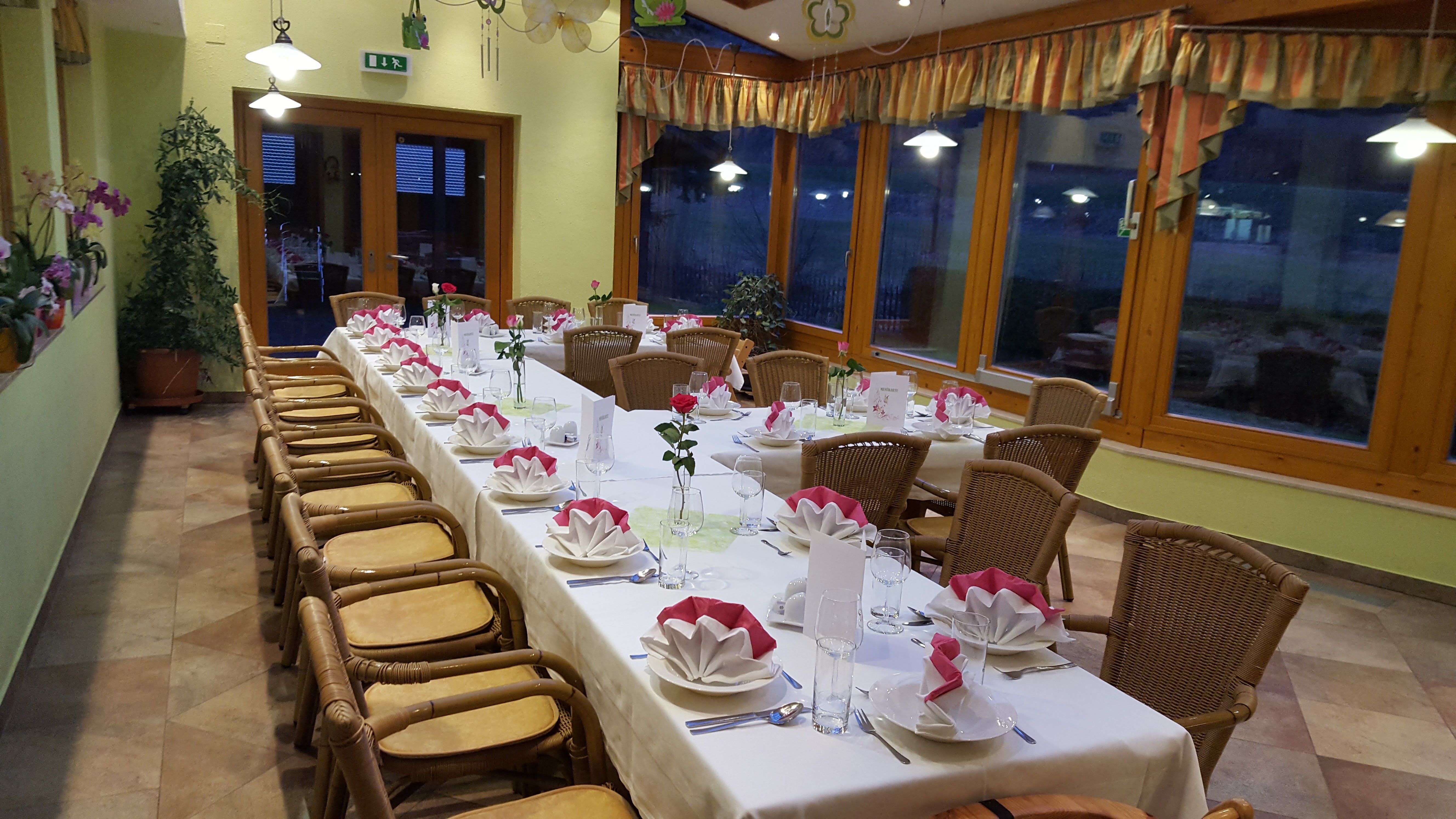 A festively laid table in a winter garden with folded napkins and flowers.