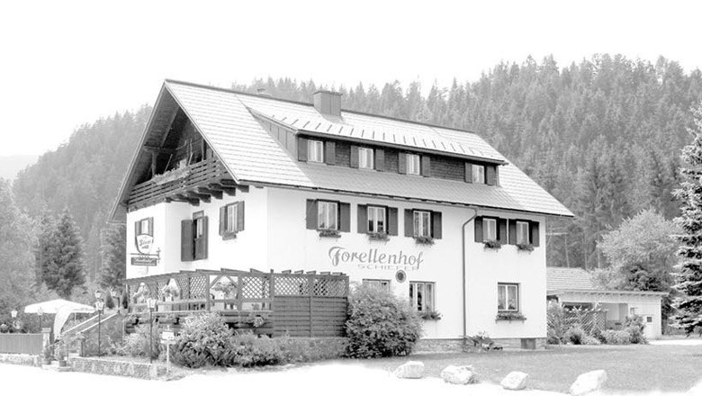 A traditional inn with the inscription 'Forellenhof Schiefer' against a forest background.