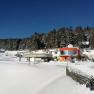 Chairlift station in Mönichkirchen in winter with snow-covered terrain and forest in the background.