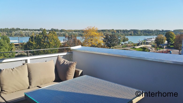 Balcony with a view of the passing Danube and balcony furniture