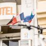 Entrance of a hotel with several flags and a bicycle in the foreground.