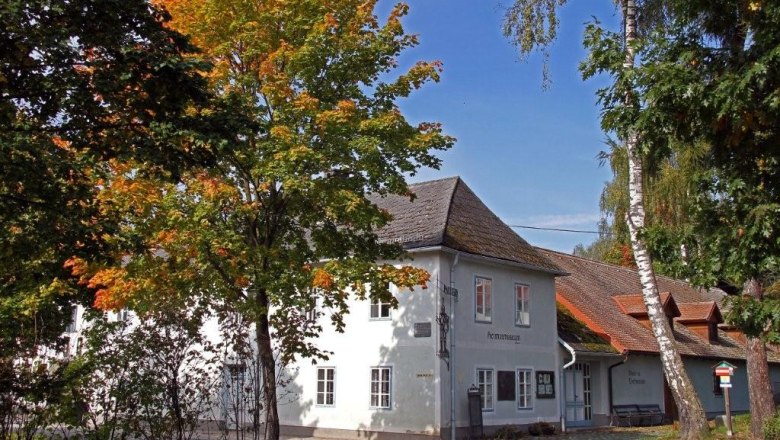 A white building with the inscription 'Heimatmuseum', surrounded by trees with autumn leaves.