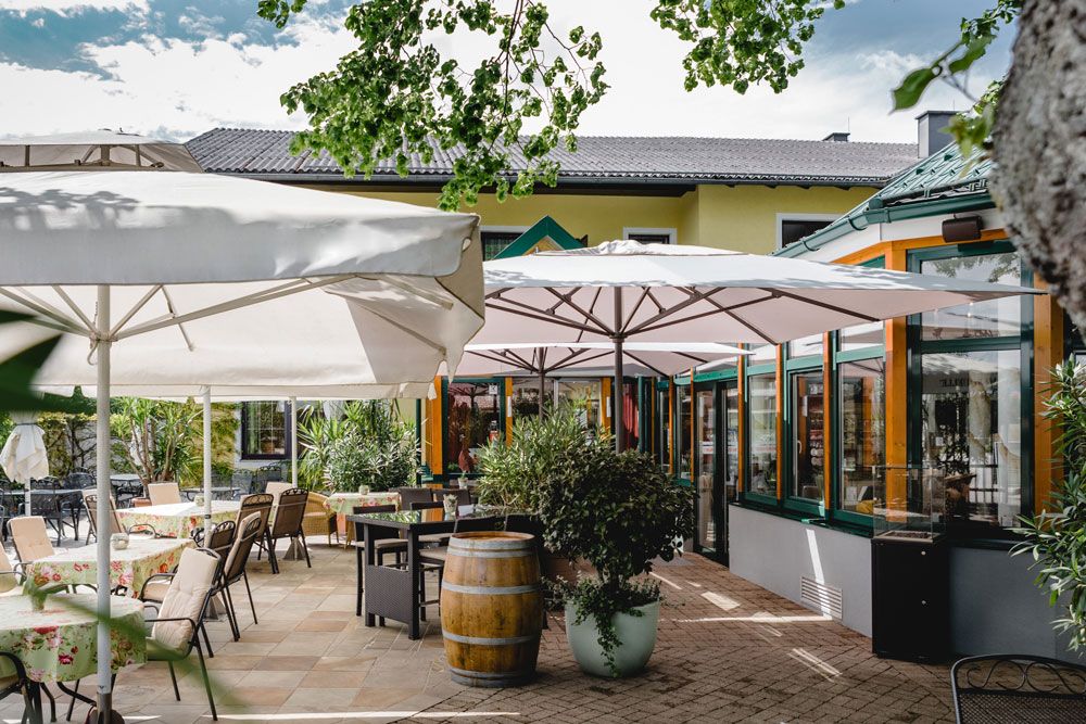 Outdoor area of a restaurant with tables, chairs and parasols.