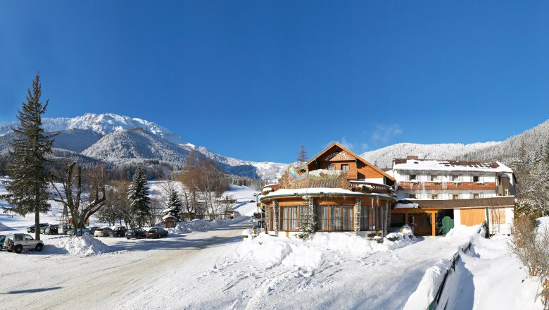 Trout farm, © Forellenhof, Martin Wanzenböck Winter landscape with Hotel Forellenhof in front of snow-covered mountains and a blue sky.