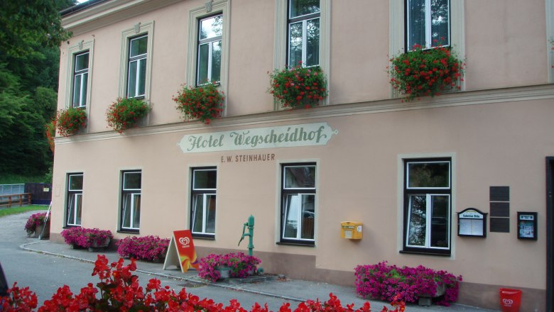 Facade of the Hotel Wegscheidhof with flower boxes and signs.