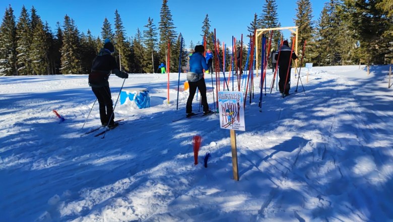 Skiers in the Skills Park at the Nordic Arena, surrounded by trees and snow.
