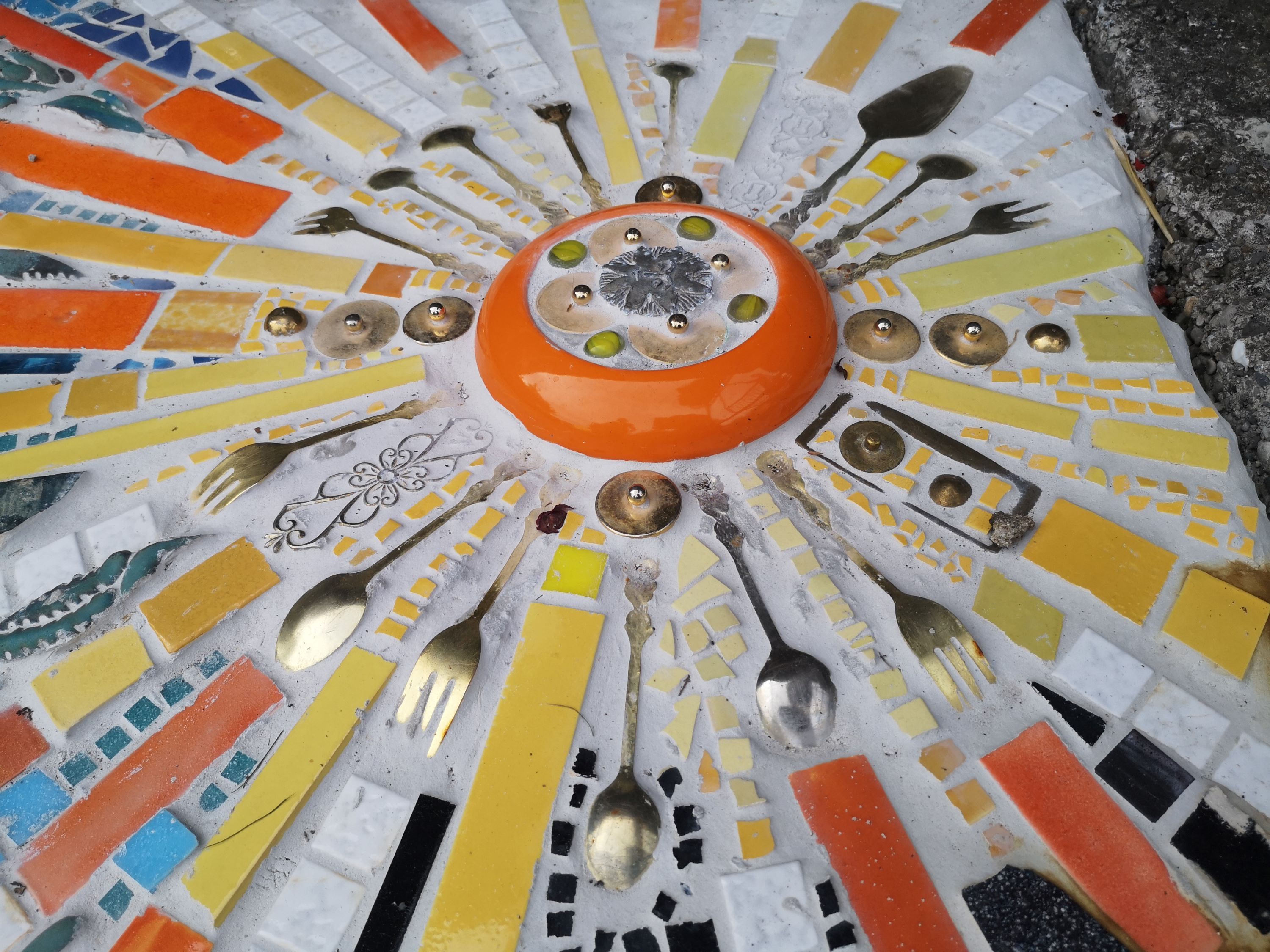 Colorful mosaic with cutlery and ceramic pieces in the shape of the sun.
