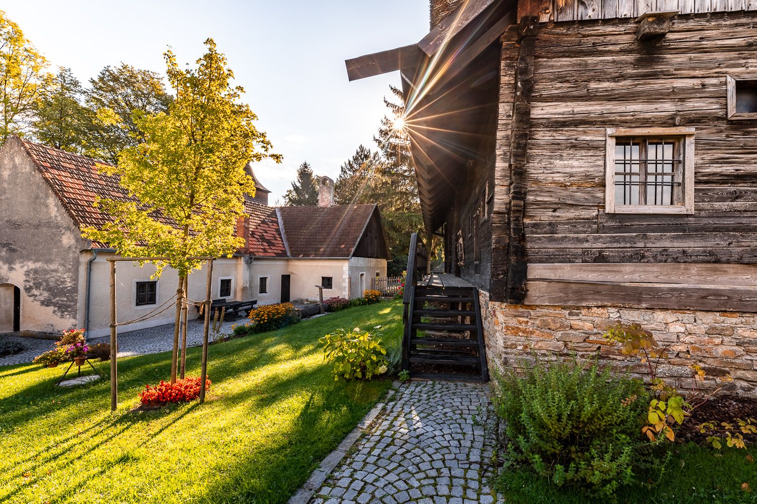 Traditional buildings and green area in the Krumbach museum village at sunset.