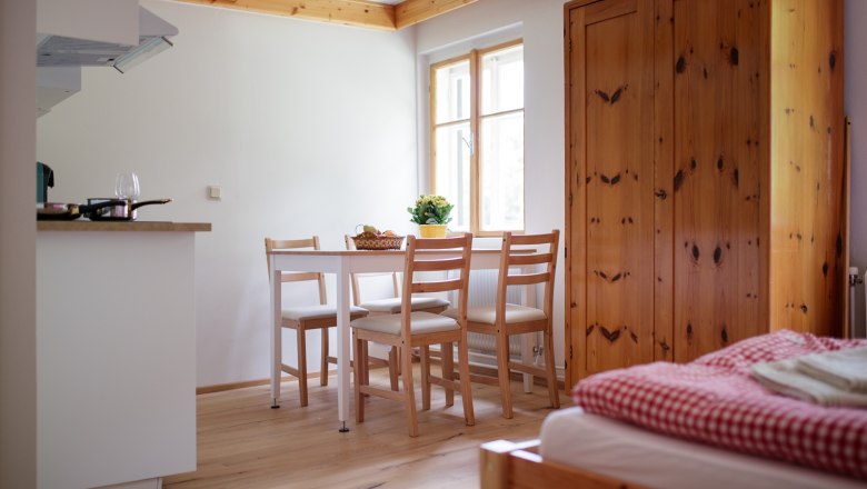 Interior view of a cozy vacation apartment with wooden furniture, dining table and bed.