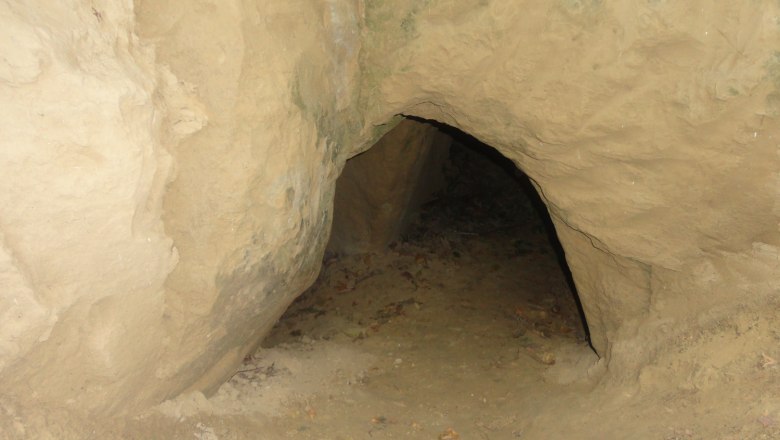 Entrance to a small cave in sandy rock.
