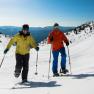 Two people snowshoeing in a snowy mountain landscape.