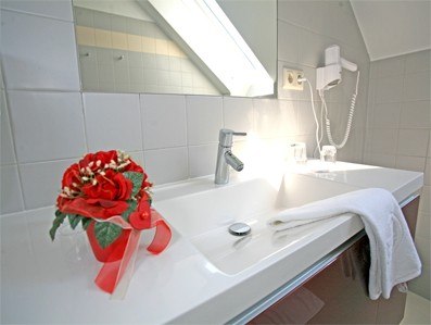 Modern bathroom with washbasin, towel, hairdryer and flower arrangement.