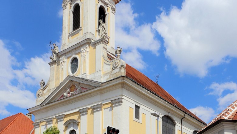 Baroque church with tower and clock against a blue sky.