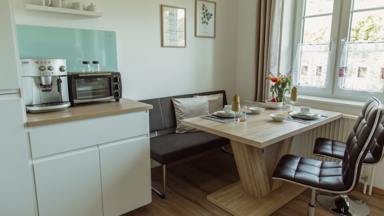 Modern kitchen with dining table, chairs and coffee machine.