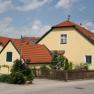 Yellow house with red roof in a rural setting.