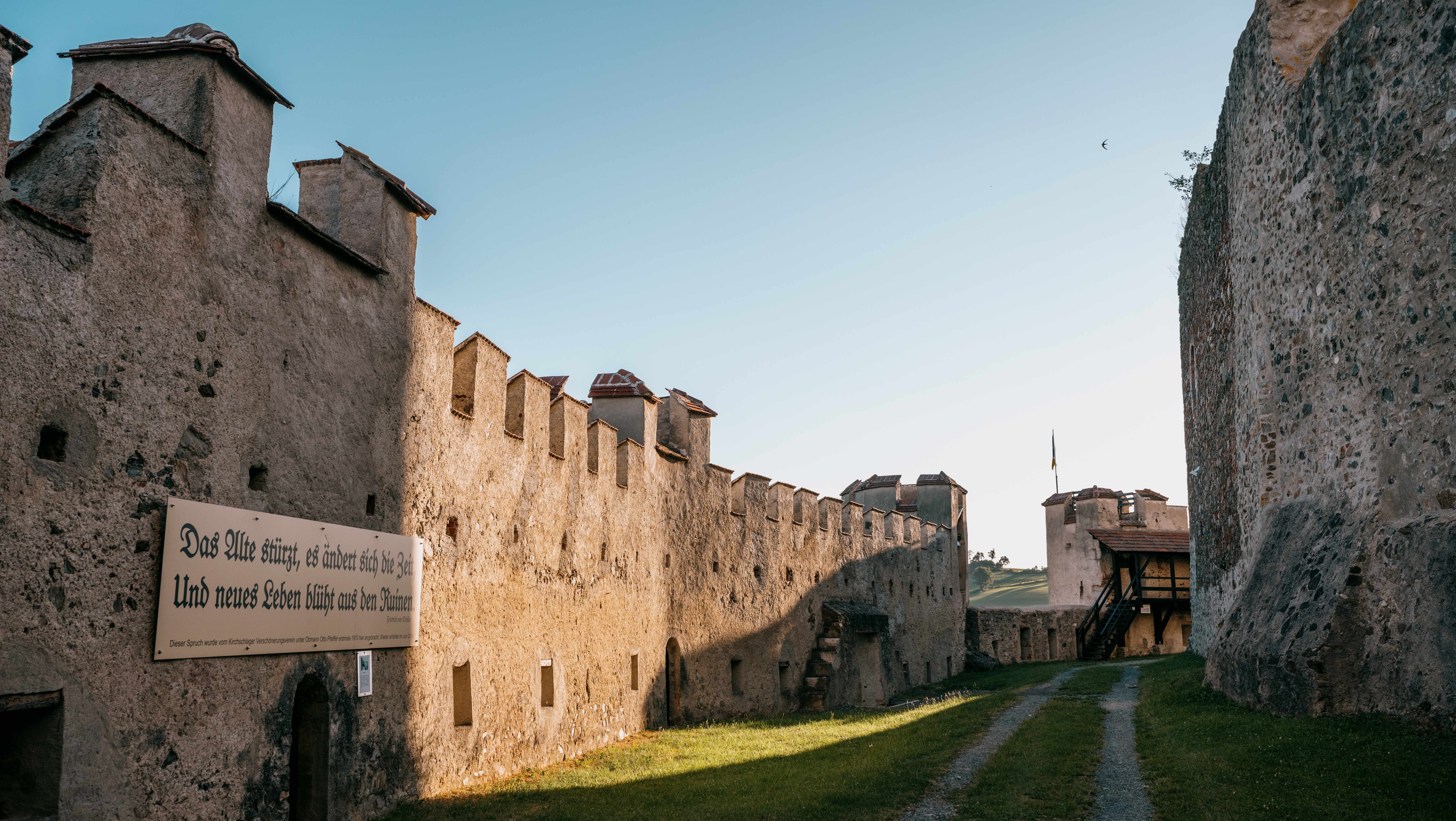 Inner corridor of the Kirchschlag castle ruins with old stone walls and a sign with an inscription.