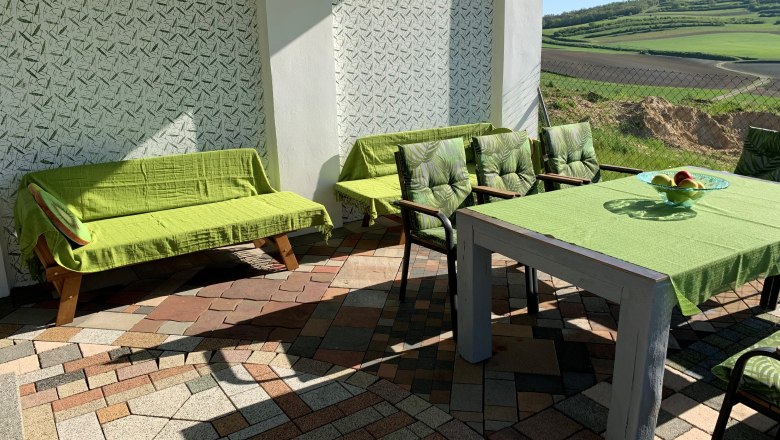 Terrace with green furniture and view of fields.