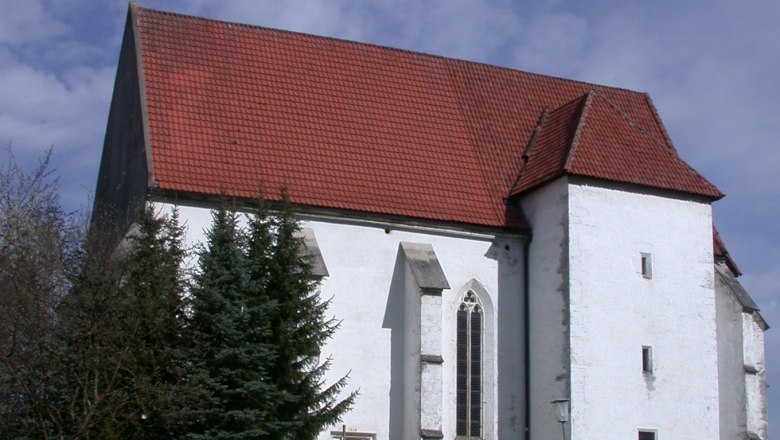 St. Andrew's Church in Kirchberg an der Pielach with a red tiled roof and white façade, surrounded by trees and a path in the foreground.