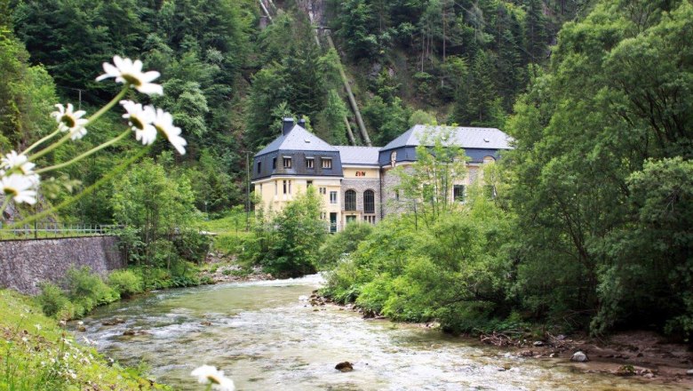 EVN's Wienerbruck power plant in a green landscape with a river.