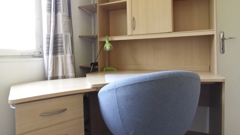 A modern desk with a gray office chair and a shelf with drawers and compartments.