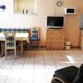 Kitchen with corner bench, table, chairs, TV, microwave and cupboards.