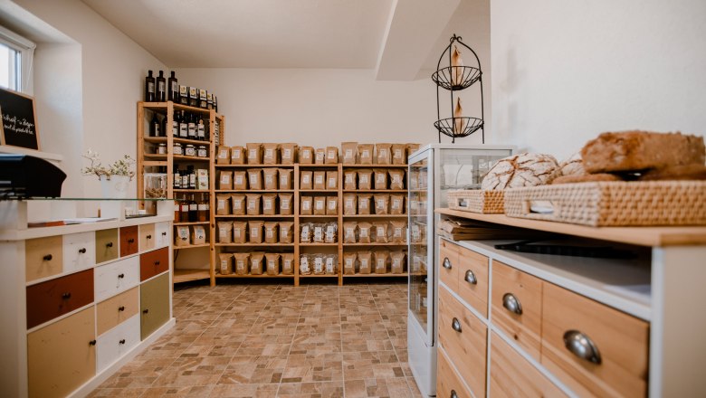 Interior view of an organic farm store with shelves full of products and a counter with bread.