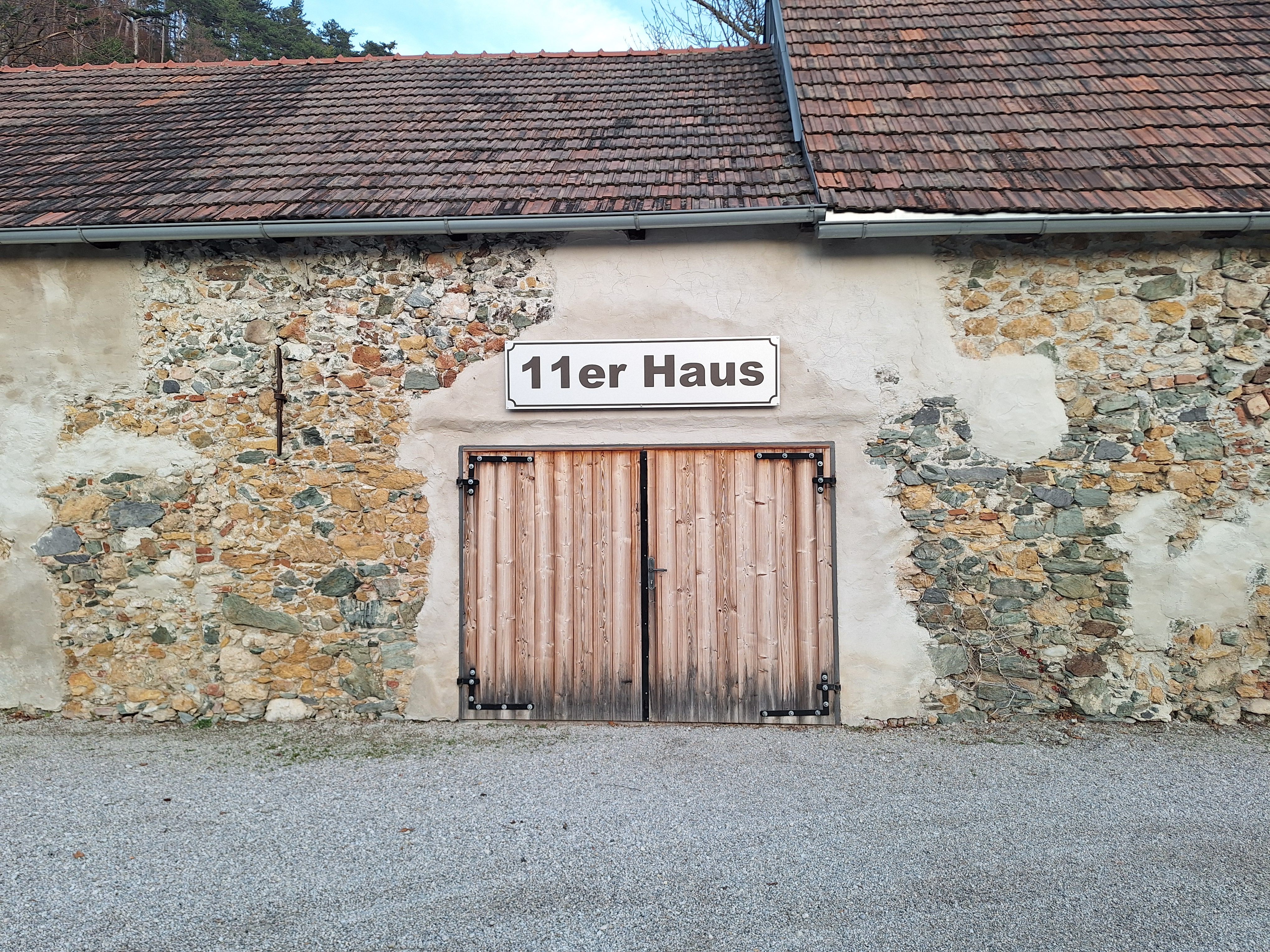 Exterior view of the 11 house with wooden gate and stone wall.