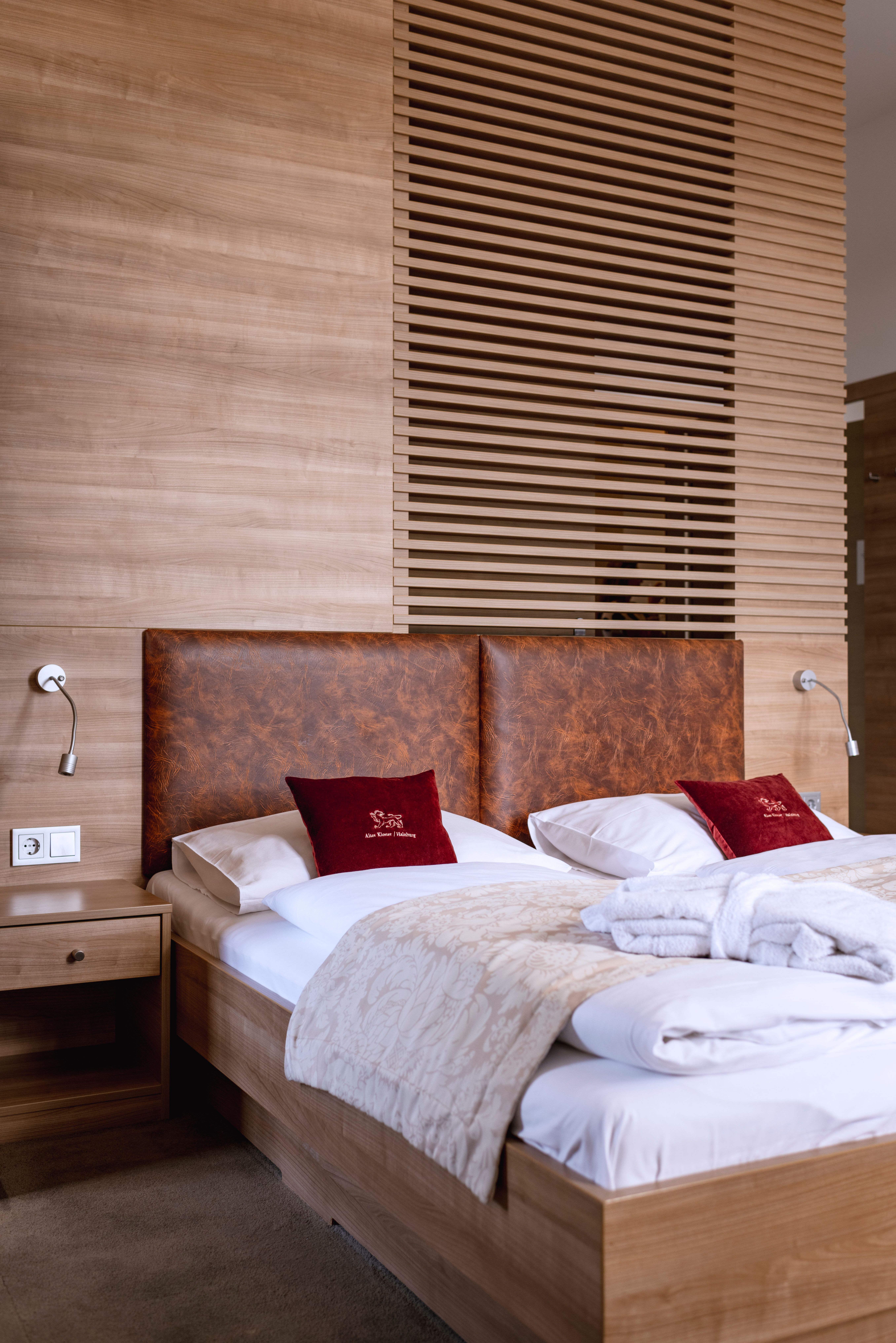 Two people in bathrobes have breakfast in bed with champagne and dessert.