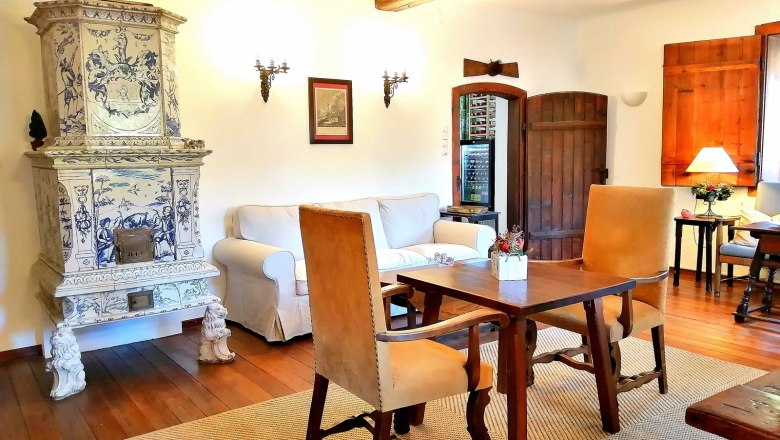 Cozy room with antique tiled stove, wooden furniture and carpet.
