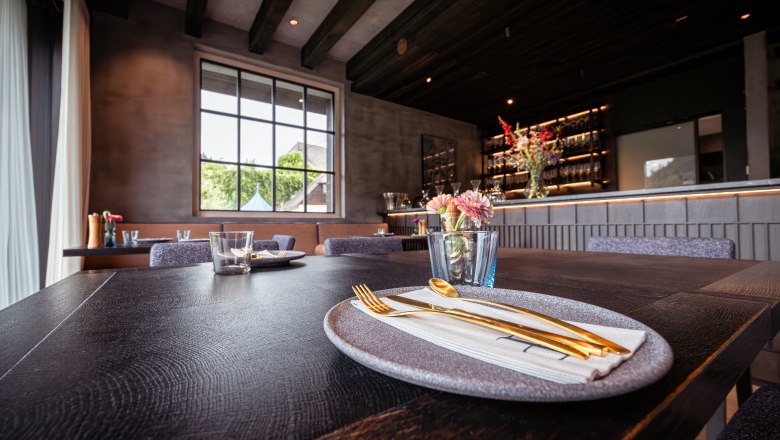 Elegant restaurant with laid table, gold-colored cutlery and flowers.