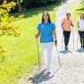 Three people Nordic walking on a gravel path in a green park. One of the people is a trainer from the Königsberg health resort.