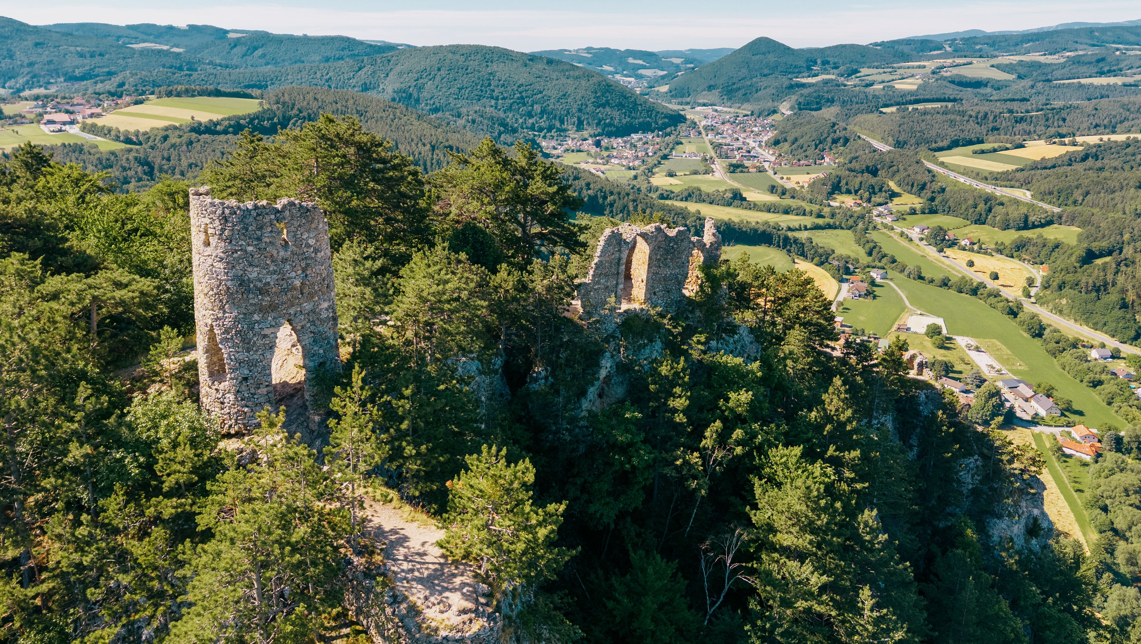 Aerial view of the Türkensturz ruins amidst wooded hills and green valleys.