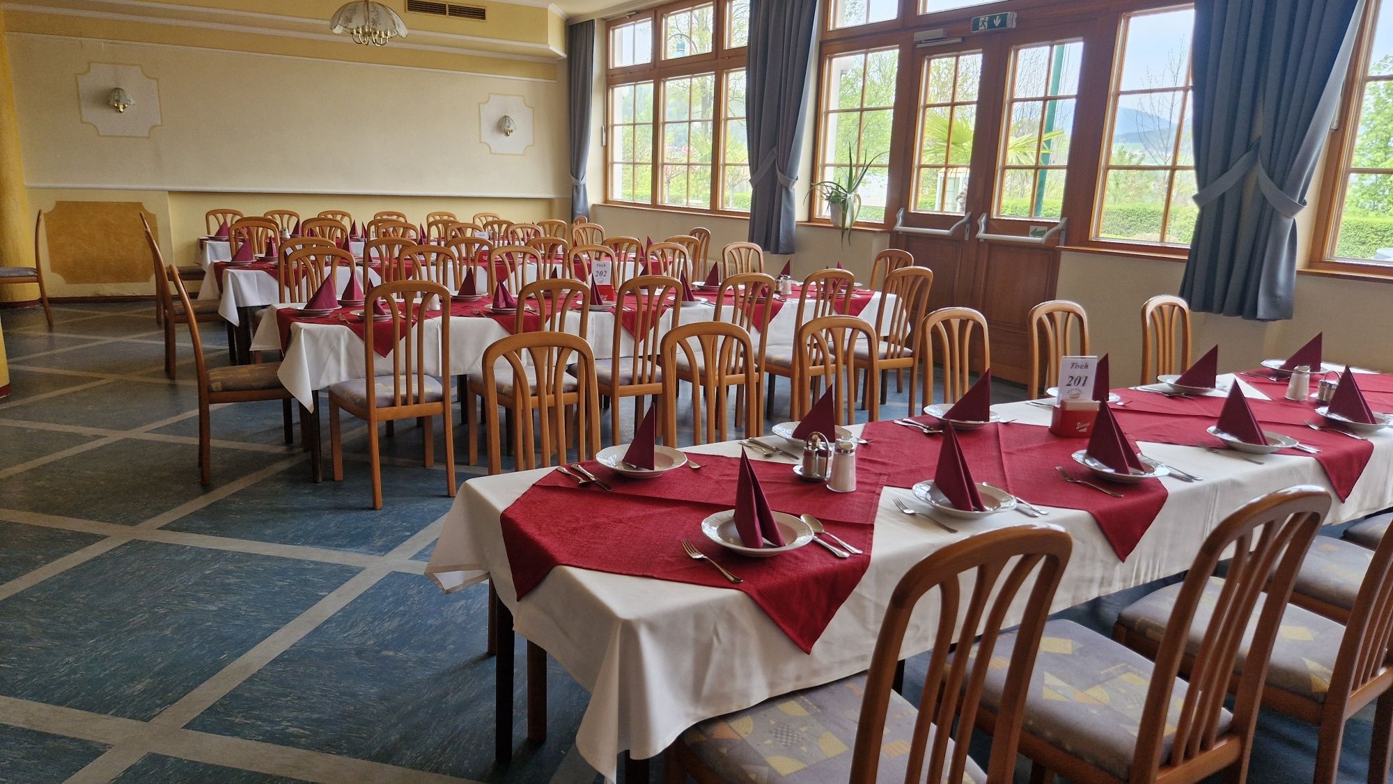 A large, festively decorated hall with wooden furniture and red tablecloths.