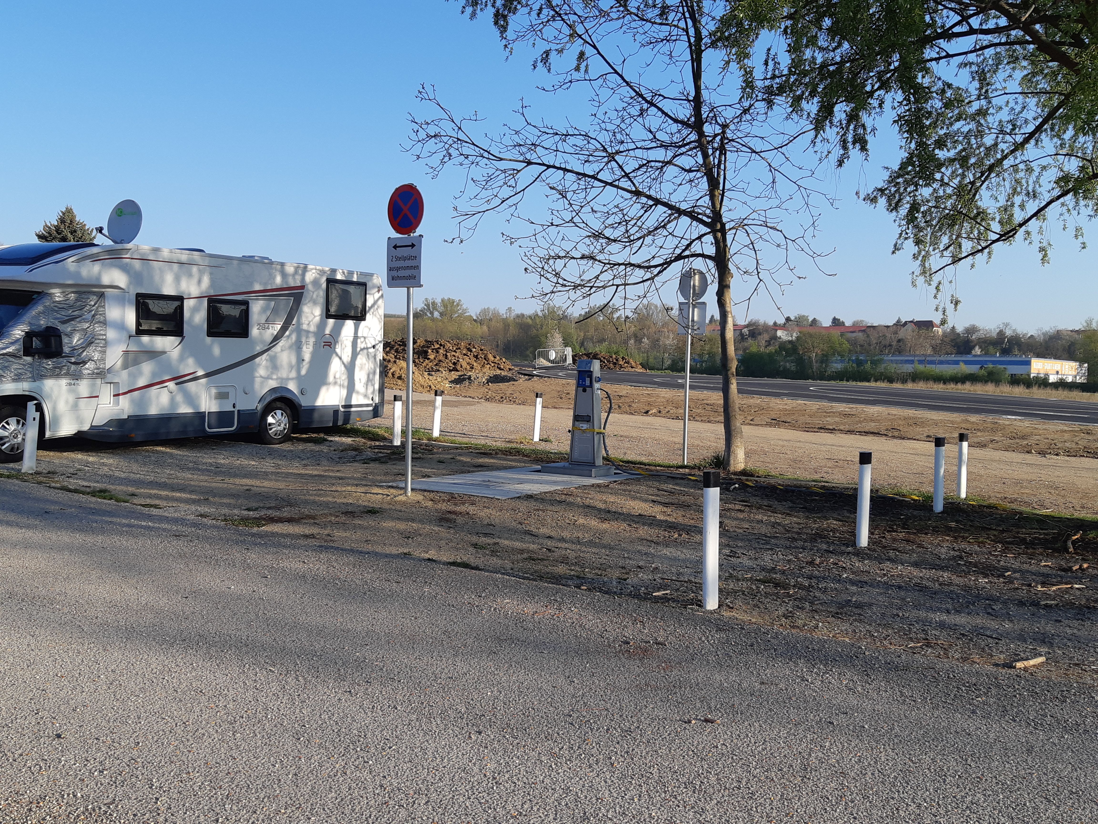 Motorhome on a pitch with signs and trees.