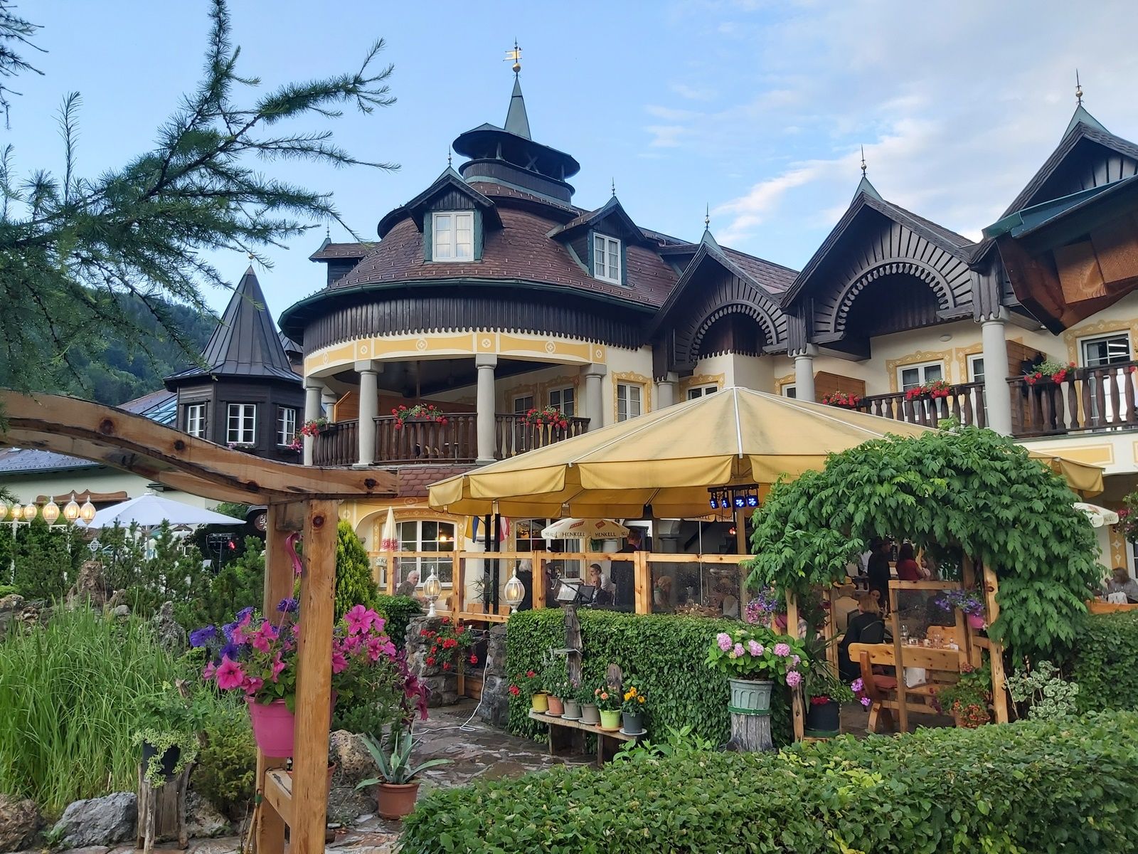 A traditional building with wooden balconies and a yellow parasol in the garden.