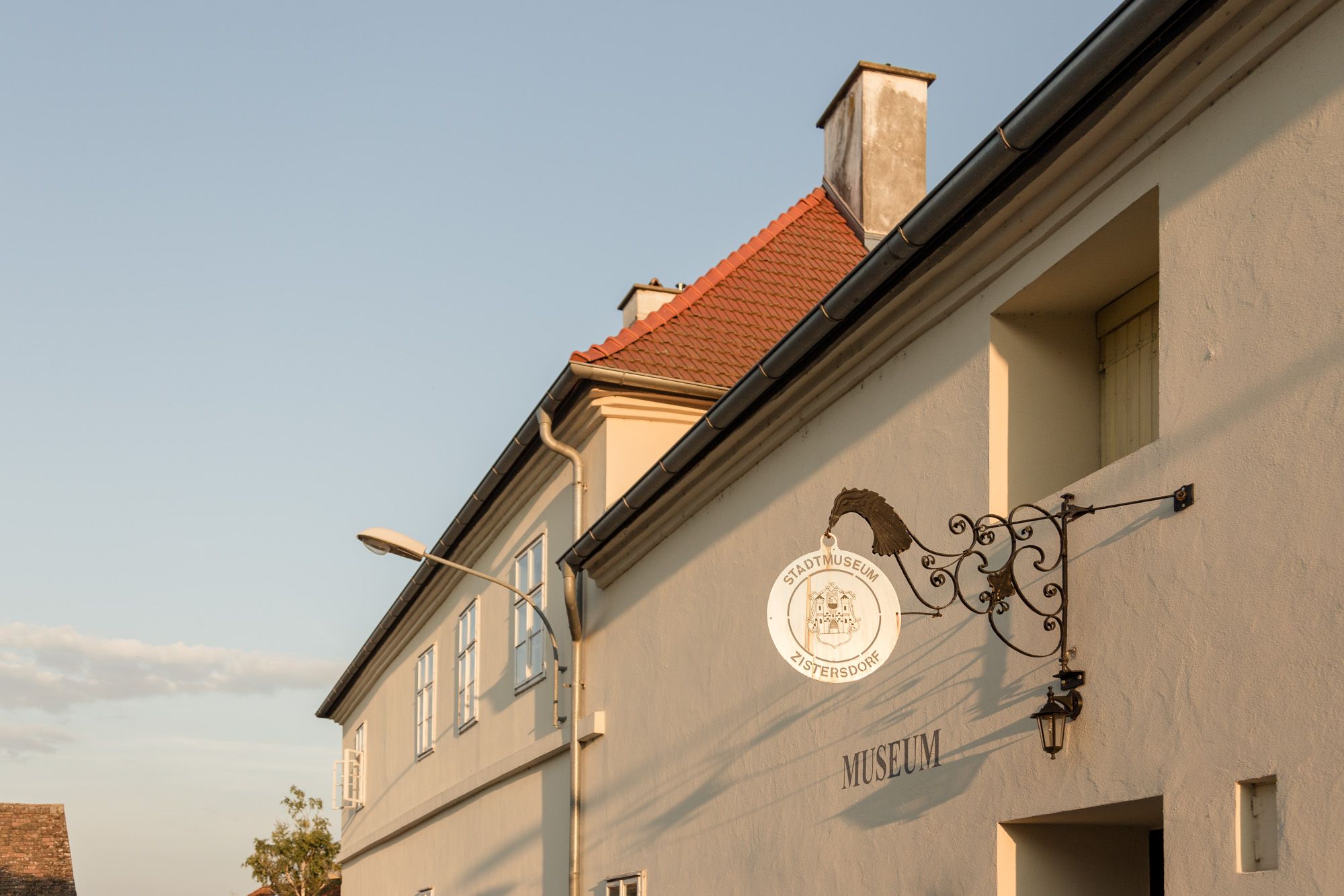 Exterior view of the Zistersdorf town museum with a decorative sign and a lamppost in the foreground.