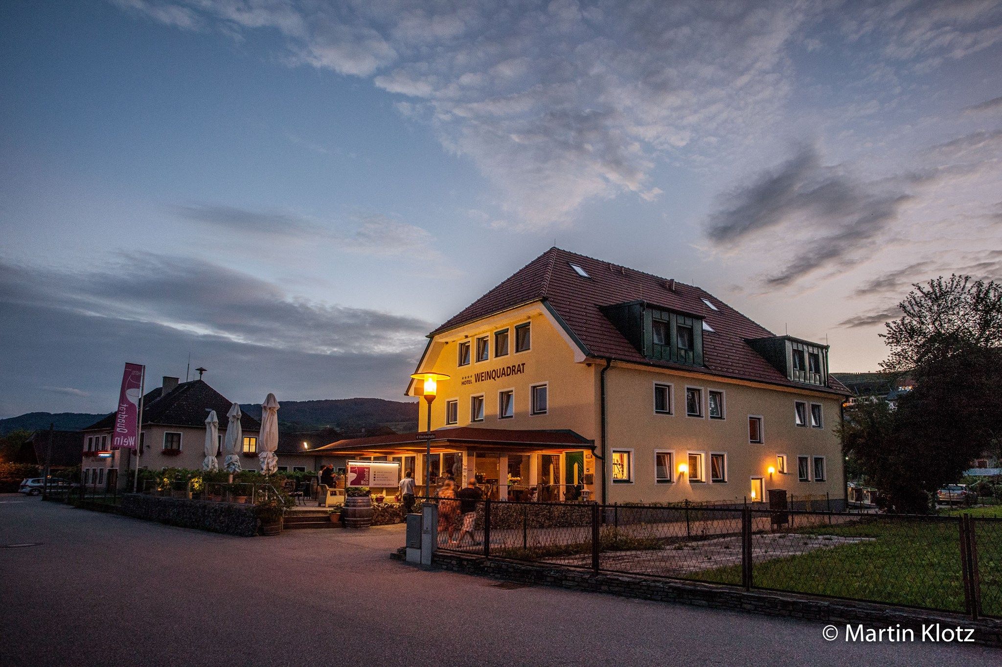 Exterior view of the Hotel Weinquadrat at dusk with illuminated terrace.
