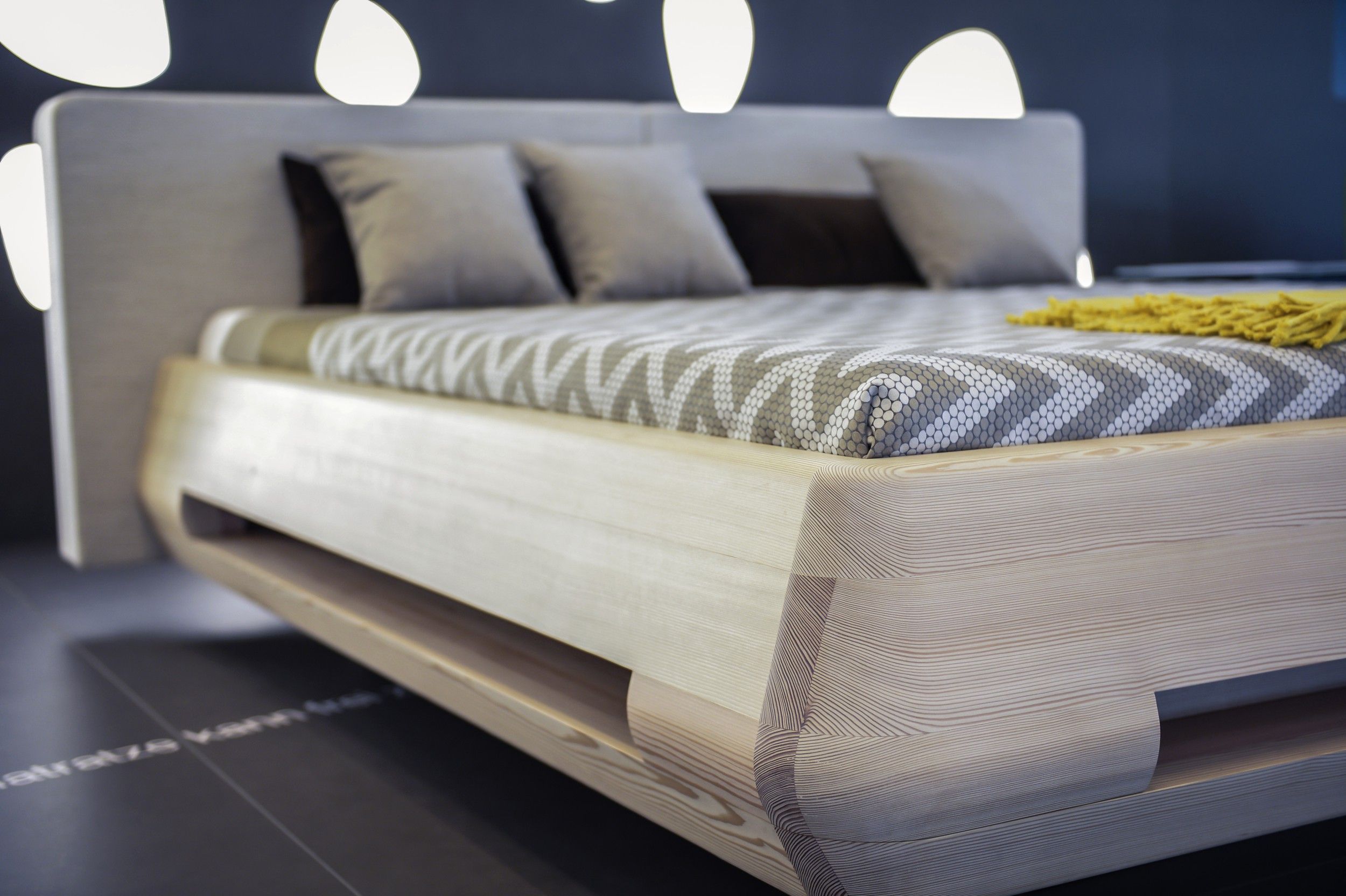 Modern bed with wooden frame and patterned comforter cover.