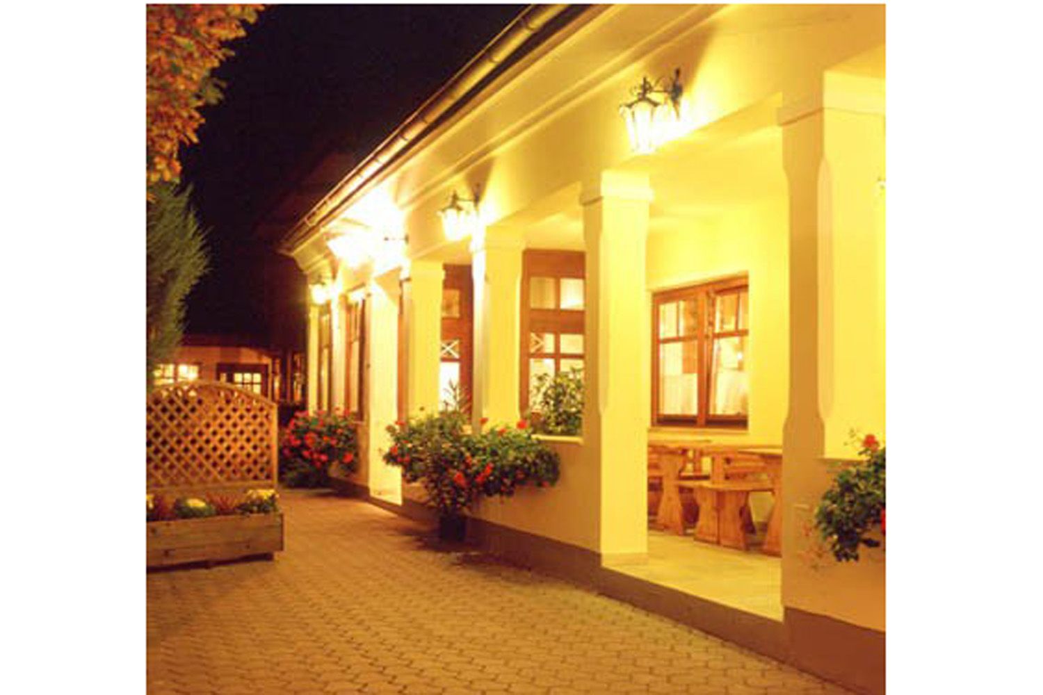Illuminated entrance area of a traditional building with columns and flowers.