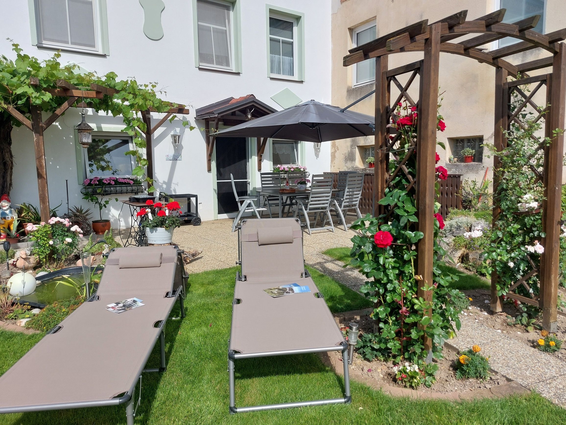Garden with sun loungers, pergola and flowers.