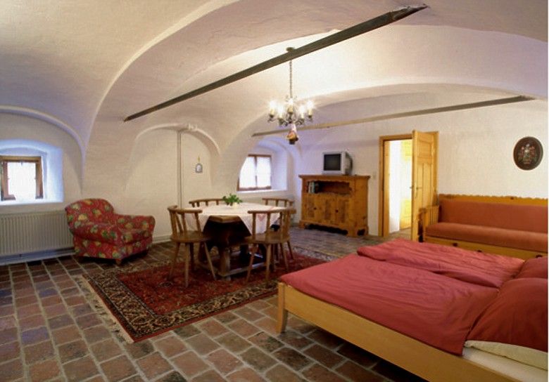 Comfortable room with wooden furniture, double bed, dining table and TV.