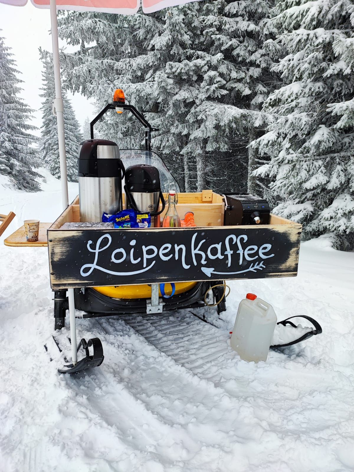 Mobile coffee stand in the snow with the inscription 'Loipenkaffee'.