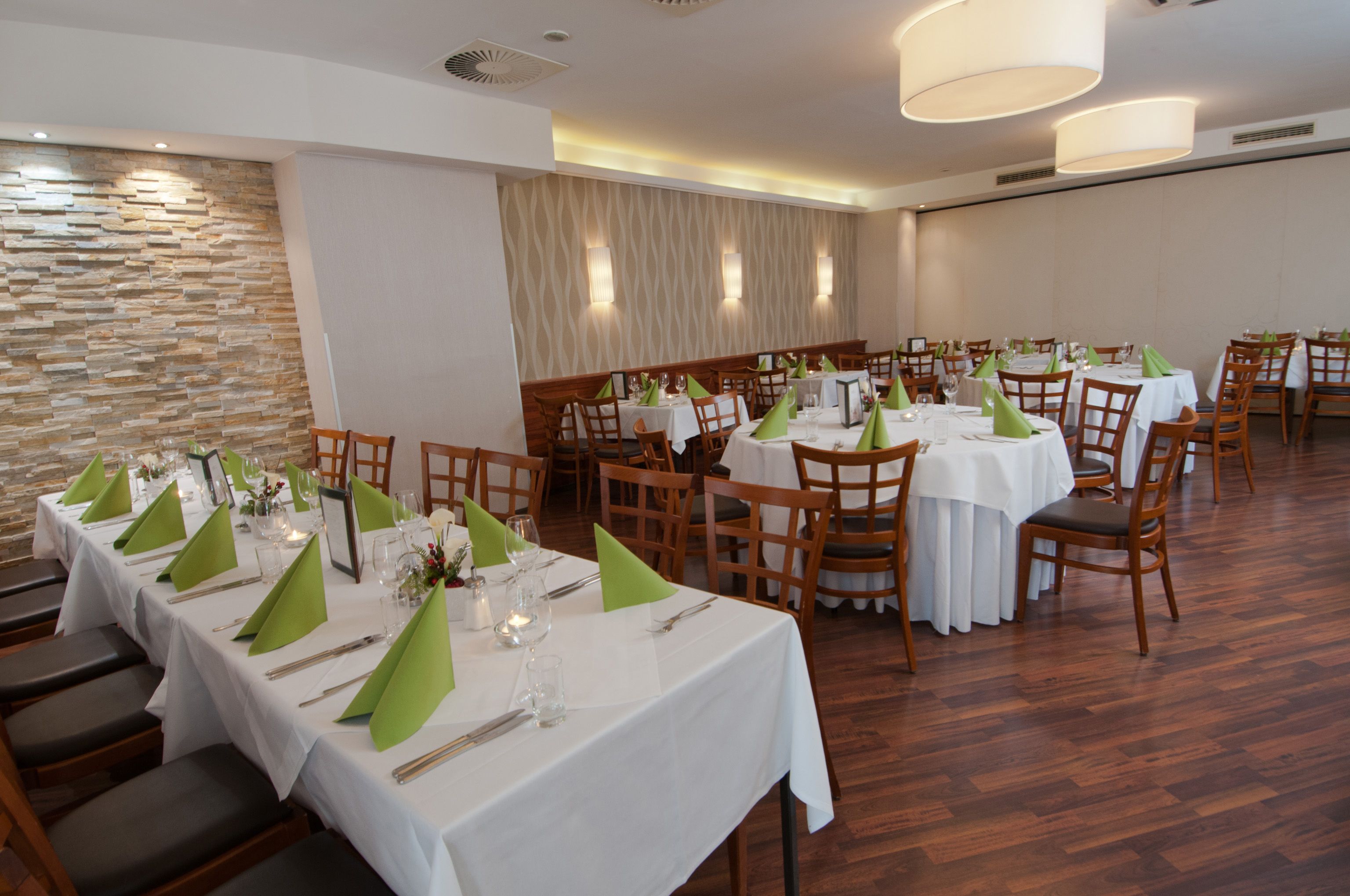 Elegant restaurant with laid tables and green napkins.