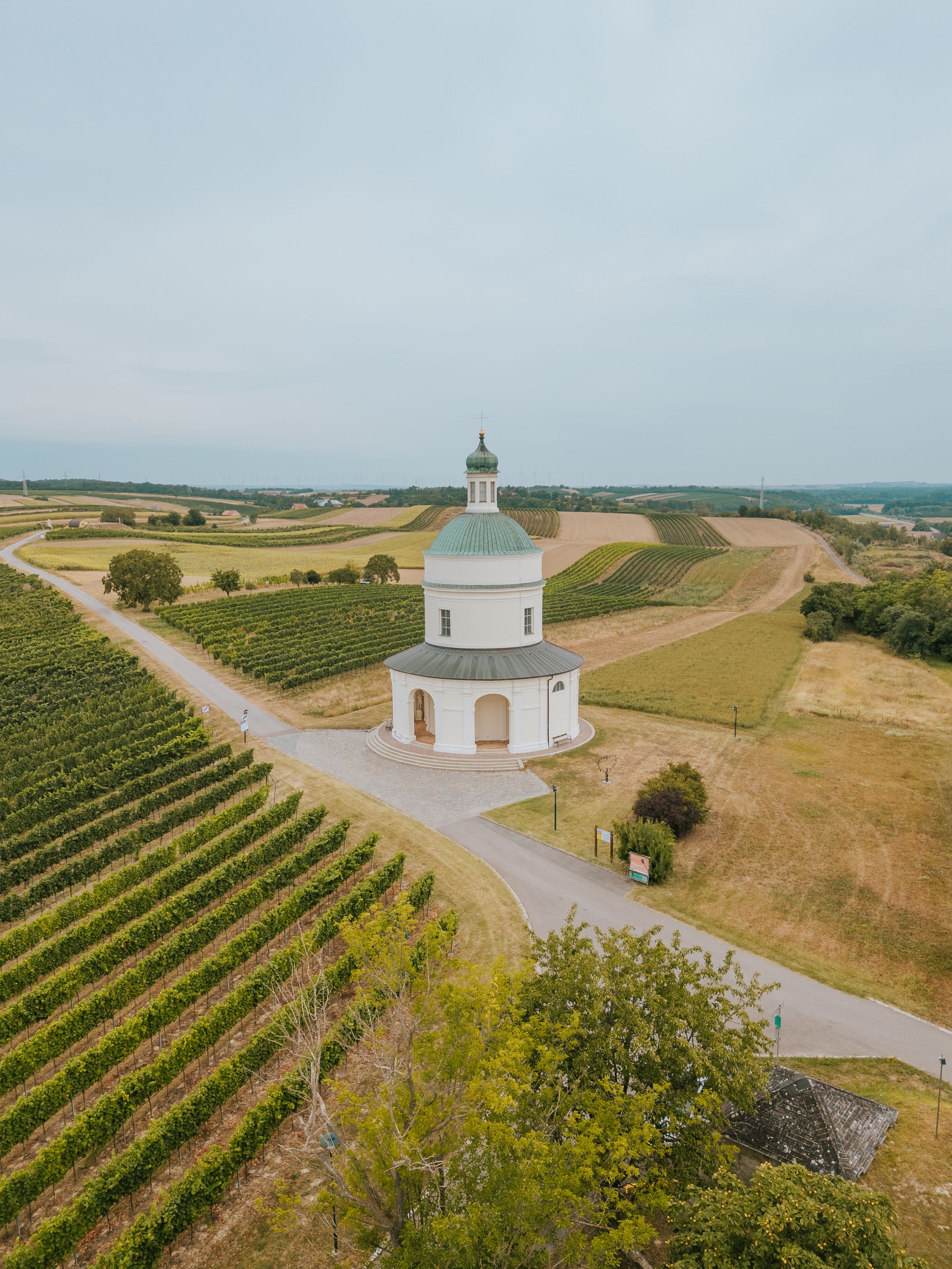 Aerial view of the Rochus Chapel on the Rochusberg in Mannersdorf, surrounded by vineyards and fields.