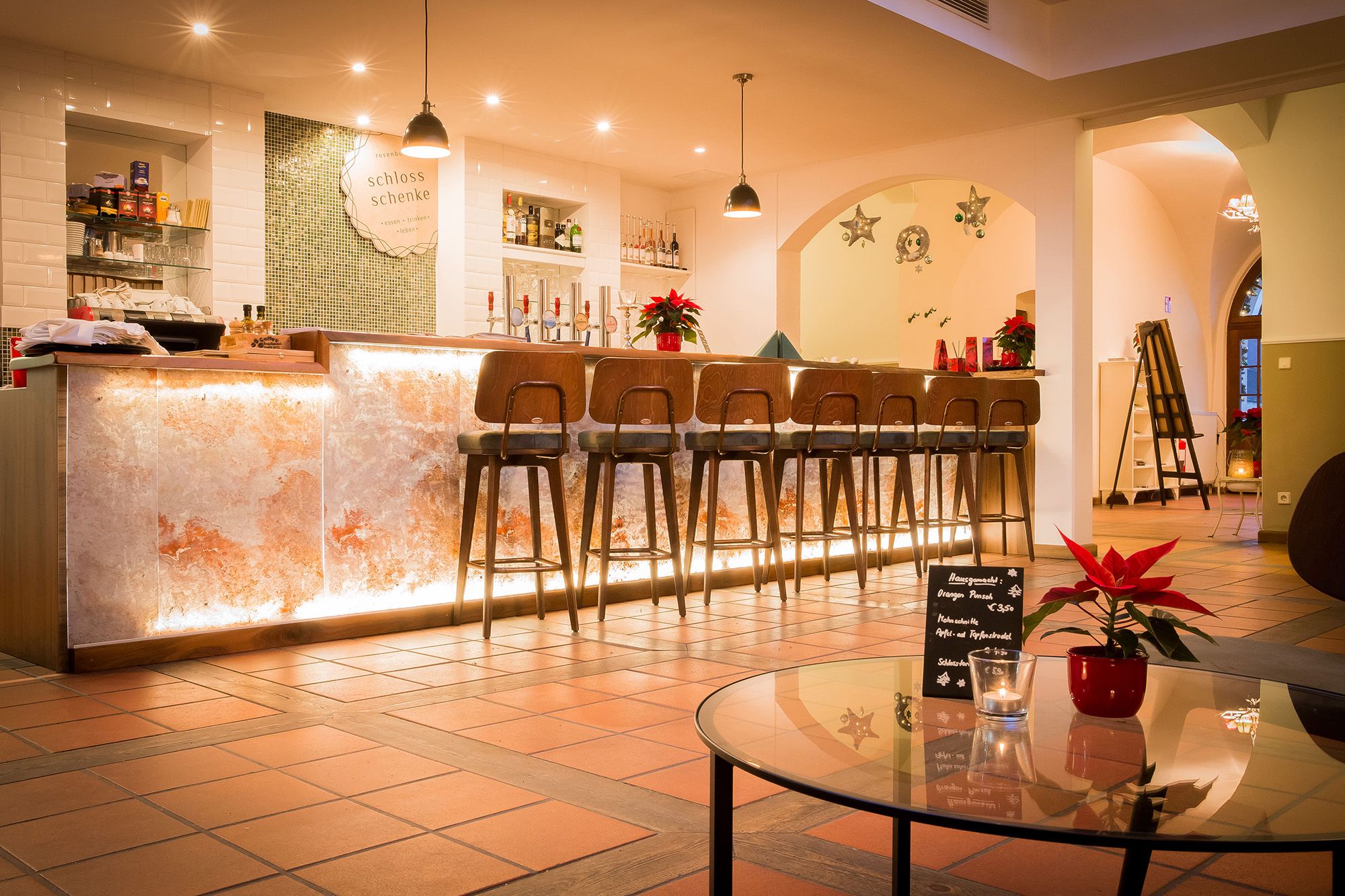 Elegant bar with illuminated counter and high stools, decorated with poinsettias.