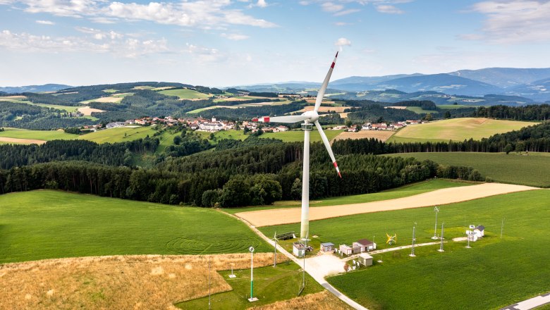Landscape with wind turbine and village in the background.